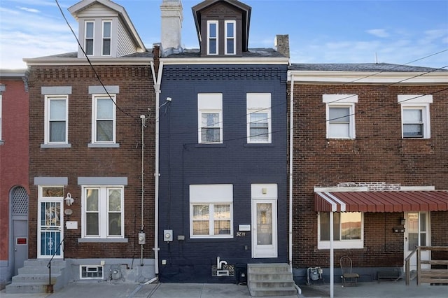multi unit property featuring entry steps, brick siding, and a chimney