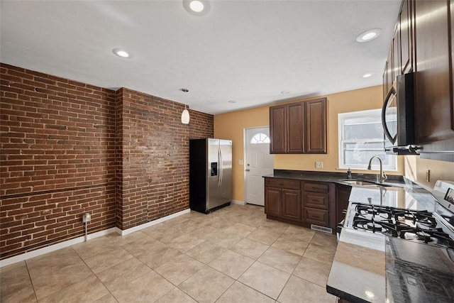 kitchen featuring stainless steel refrigerator with ice dispenser, a sink, brick wall, gas range, and black microwave
