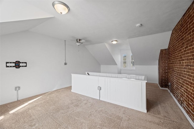 additional living space with vaulted ceiling, carpet floors, brick wall, and a ceiling fan