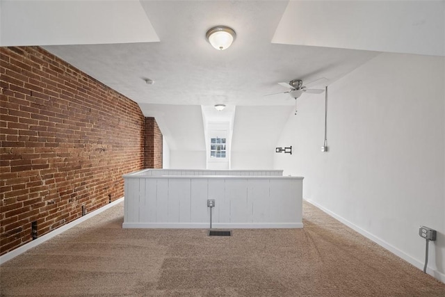 carpeted spare room with brick wall, baseboards, and ceiling fan
