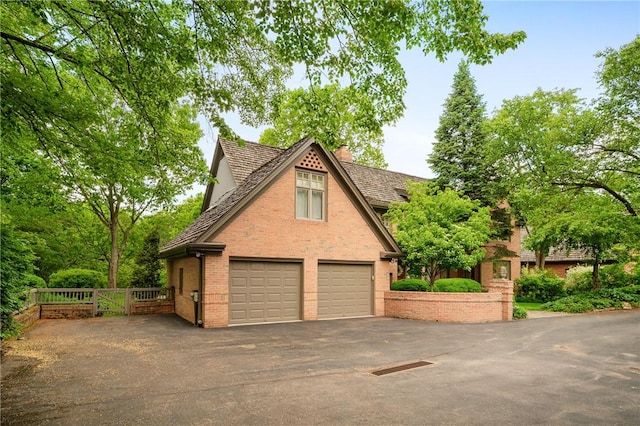 view of front of home with brick siding, a garage, and a chimney