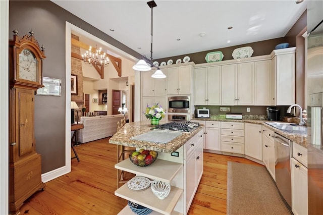 kitchen featuring open shelves, a sink, stainless steel appliances, and light wood finished floors