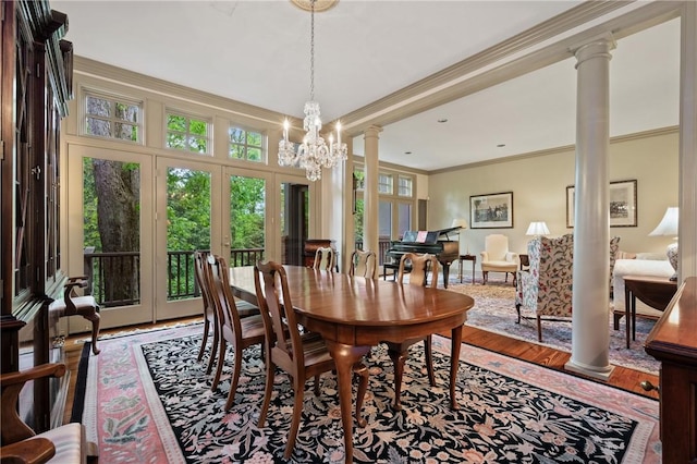 dining room with french doors, ornate columns, ornamental molding, wood finished floors, and a chandelier