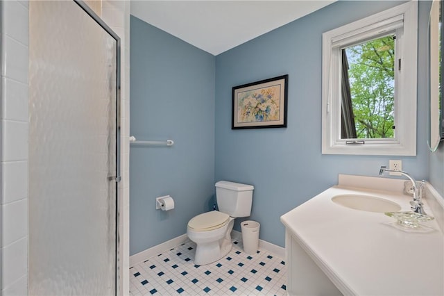 full bath featuring a sink, toilet, tiled shower, and baseboards