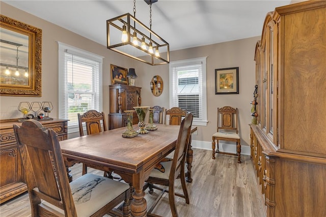 dining space featuring light wood-style flooring, plenty of natural light, baseboards, and a chandelier