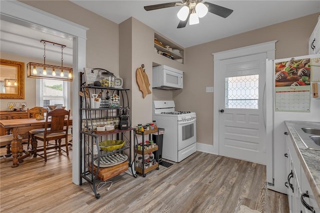 kitchen featuring white appliances, ceiling fan, light wood finished floors, and white cabinets