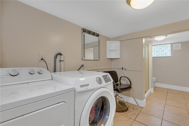 clothes washing area with separate washer and dryer, baseboards, and light tile patterned floors