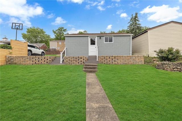 view of front of house with a front yard and concrete block siding