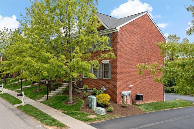 view of side of property with brick siding, cooling unit, and stairway