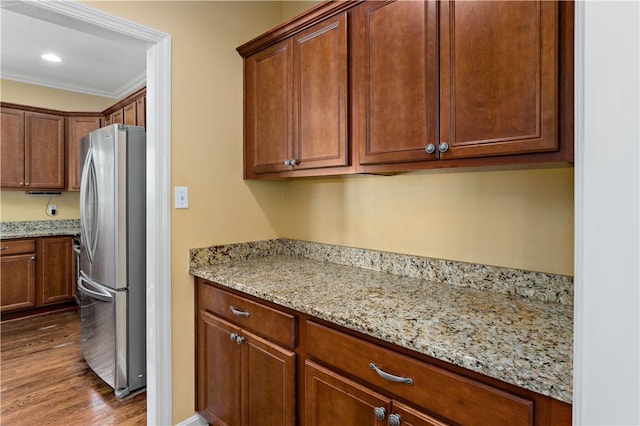 kitchen featuring freestanding refrigerator, dark wood-style flooring, light stone counters, and ornamental molding