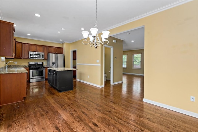 kitchen featuring stainless steel appliances, a sink, ornamental molding, a kitchen island, and a chandelier