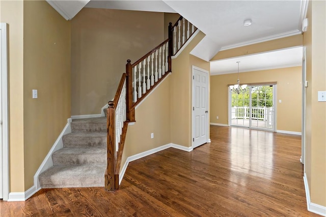 stairs with a chandelier, wood finished floors, baseboards, and crown molding