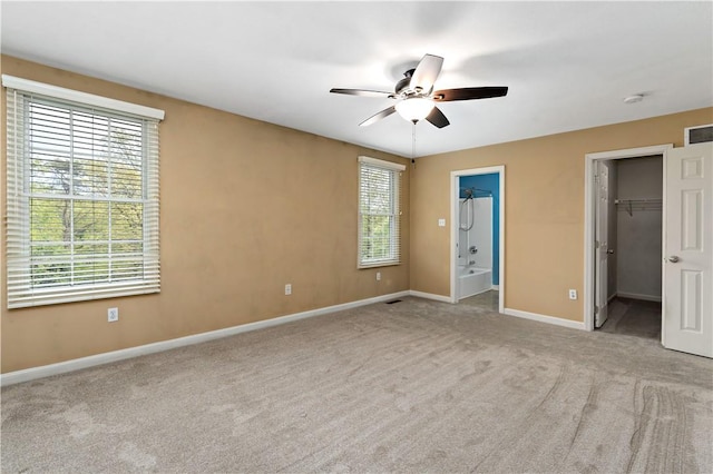 unfurnished bedroom featuring a walk in closet, baseboards, carpet, and ensuite bathroom