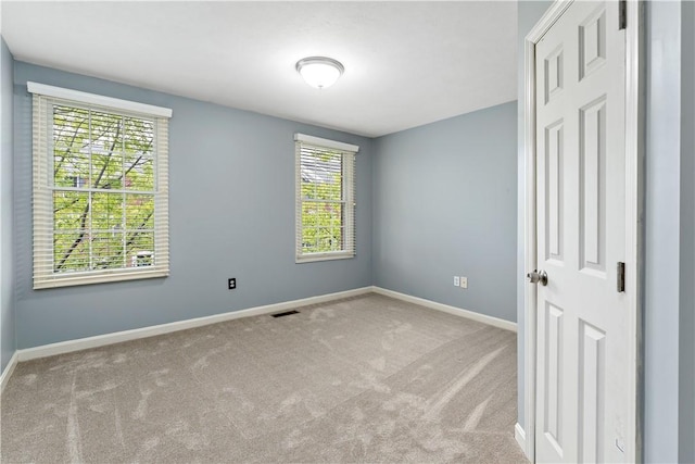 carpeted empty room featuring baseboards