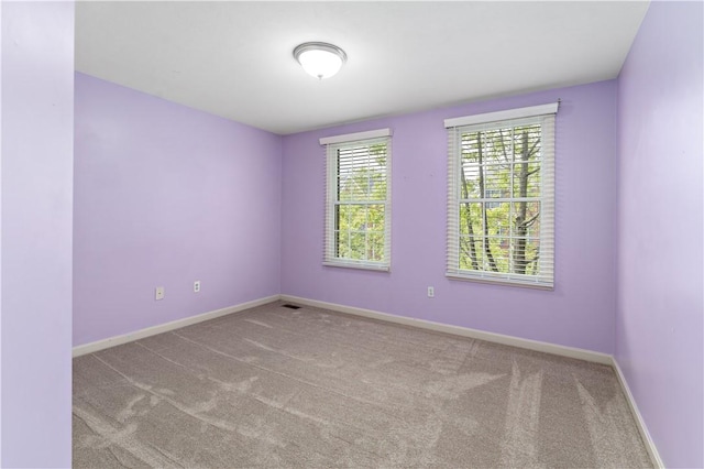 carpeted spare room featuring baseboards