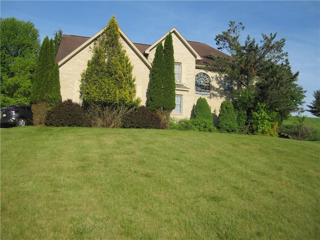 view of side of home featuring a lawn and brick siding
