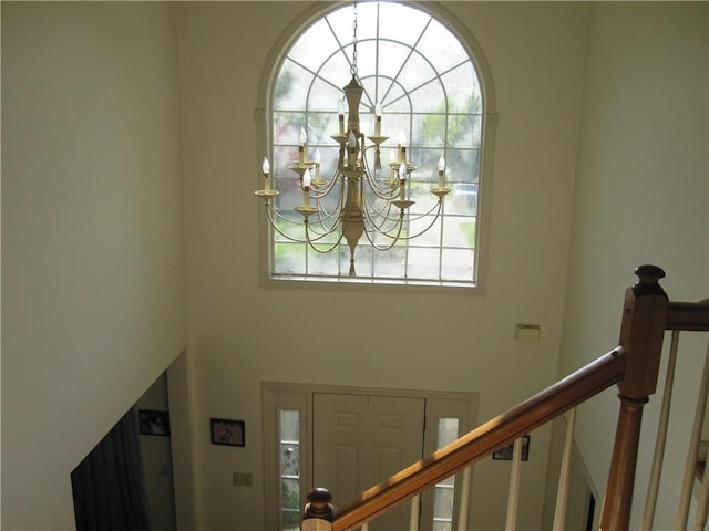 foyer entrance with healthy amount of natural light, a chandelier, and stairs