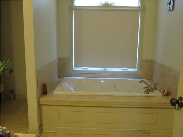 bathroom featuring a garden tub, toilet, and tile patterned floors