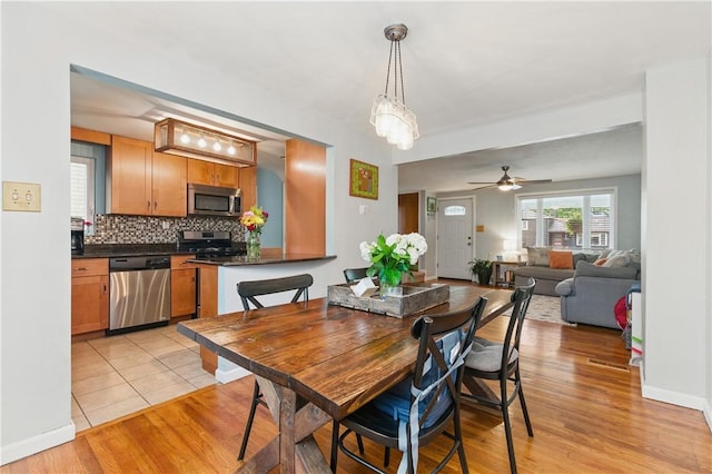 dining room featuring light wood-style flooring, a ceiling fan, and baseboards