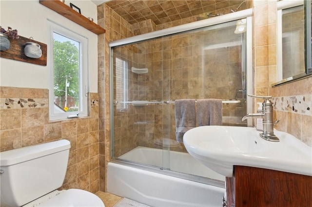 full bathroom featuring tile walls, enclosed tub / shower combo, and toilet