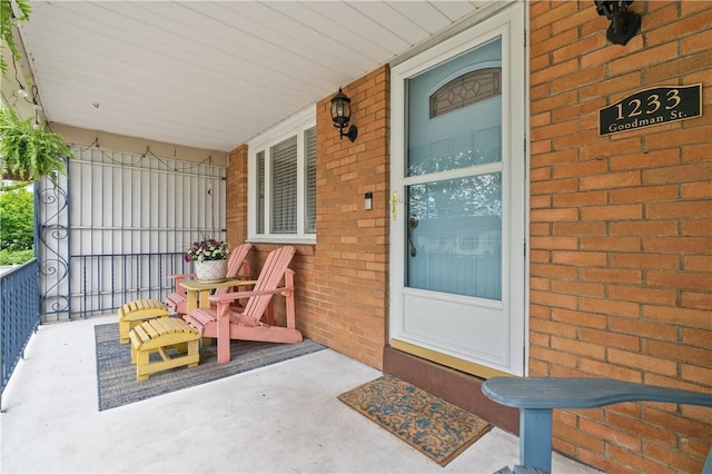 view of exterior entry featuring a porch and brick siding
