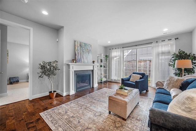 living area featuring a glass covered fireplace, wood finished floors, baseboards, and recessed lighting