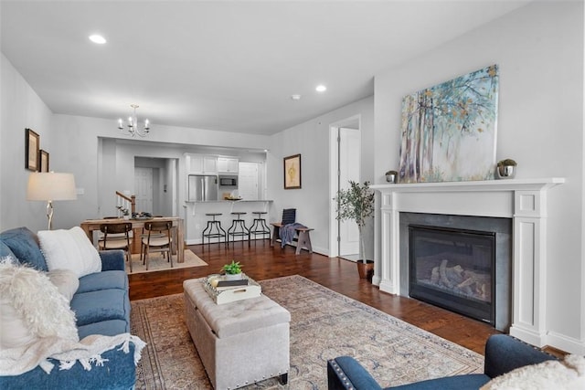 living room featuring a chandelier, dark wood-type flooring, a glass covered fireplace, recessed lighting, and baseboards