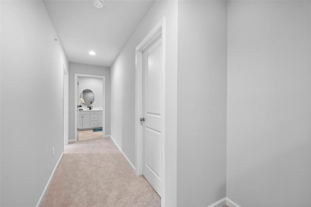 corridor featuring baseboards and light carpet