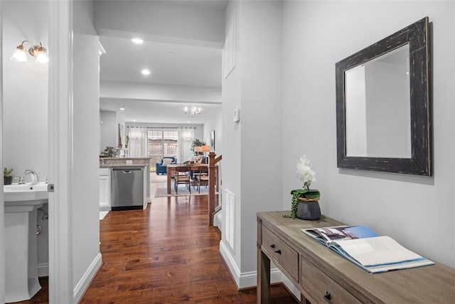 hallway featuring dark wood-type flooring, recessed lighting, a sink, and a chandelier