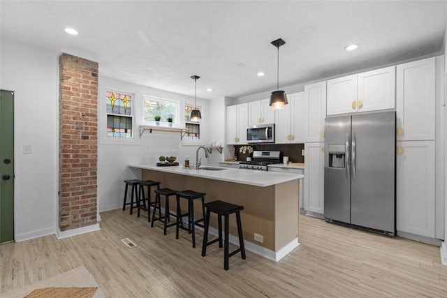 432 Iberia St, Mt Washington, PA 15211 - kitchen with stainless steel appliances, a sink, a peninsula, a breakfast bar area, and light wood finished floors