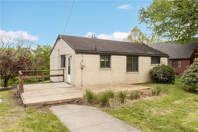 view of side of home featuring a wooden deck, a yard, a chimney, and brick siding