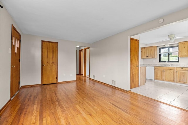 unfurnished living room with light wood-style floors, a sink, and baseboards
