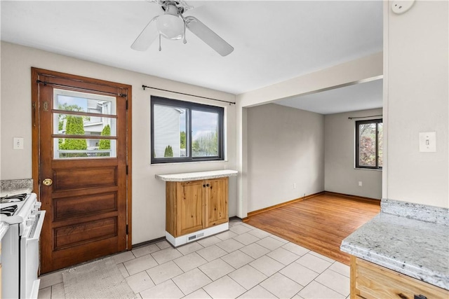 kitchen with gas range gas stove, light countertops, ceiling fan, and baseboards