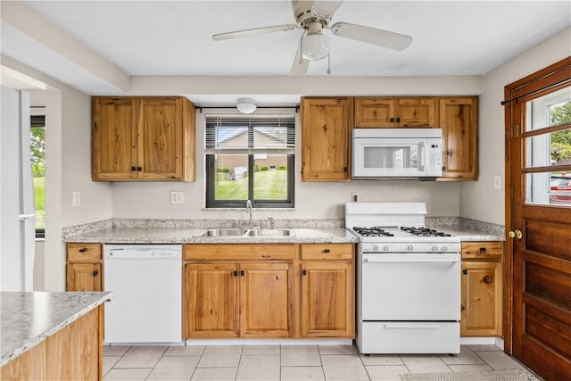 kitchen with white appliances, a sink, light tile patterned flooring, light countertops, and brown cabinets