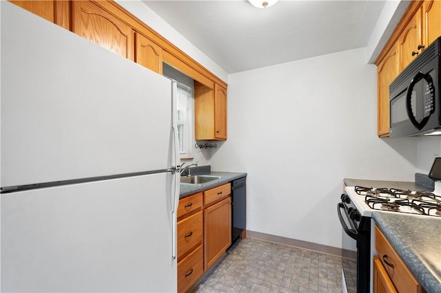 kitchen featuring black appliances, a sink, baseboards, and dark countertops