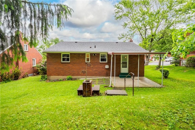 rear view of property featuring a patio area, a yard, and brick siding