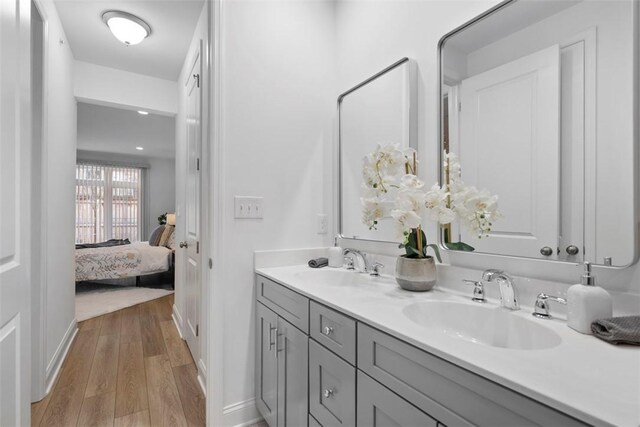ensuite bathroom with wood finished floors, double vanity, and baseboards