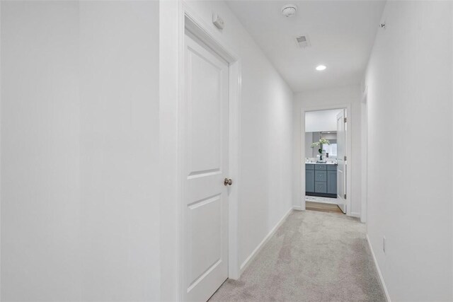 hall featuring baseboards, light colored carpet, and recessed lighting