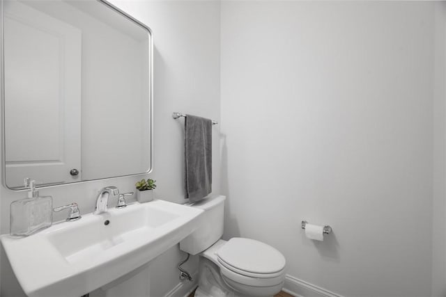 bathroom featuring toilet, a sink, and baseboards