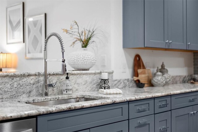 kitchen view of a sink, light stone countertops, and dishwasher