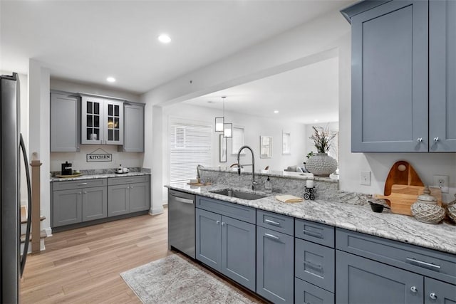 kitchen with appliances with stainless steel finishes, a sink, light wood-style flooring, glass insert cabinets, and gray cabinets