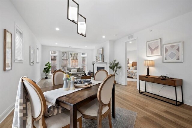 dining space featuring light wood-style floors, baseboards, a fireplace, and recessed lighting