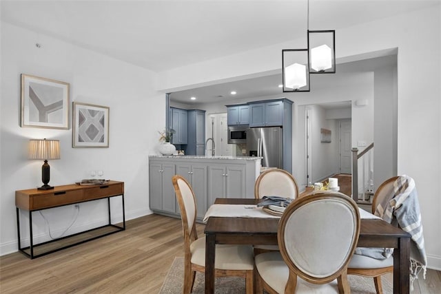 dining space featuring light wood-style flooring, baseboards, stairs, and recessed lighting