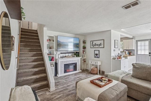 550 Mcclane Farm Rd, Chartiers, PA 15301 - living room featuring stairway, wood finished floors, a glass covered fireplace, built in features, and a textured ceiling