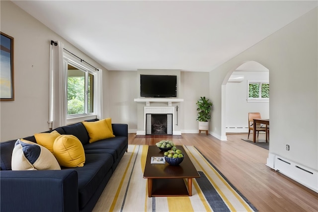 6640 Wilkins Ave, Squirrel Hill, PA 15217 - living area featuring wood finished floors, plenty of natural light, a baseboard radiator, and arched walkways