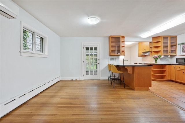6640 Wilkins Ave, Squirrel Hill, PA 15217 - kitchen featuring open shelves, a wall mounted air conditioner, a baseboard radiator, under cabinet range hood, and a kitchen bar