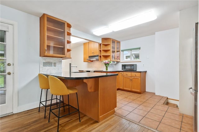 6640 Wilkins Ave, Squirrel Hill, PA 15217 - kitchen with open shelves, under cabinet range hood, black microwave, a peninsula, and backsplash