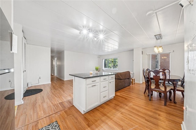 kitchen with light wood-style floors, open floor plan, dark countertops, white cabinets, and a center island