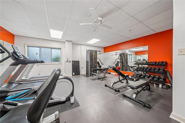 exercise room featuring a drop ceiling, ceiling fan, and baseboards