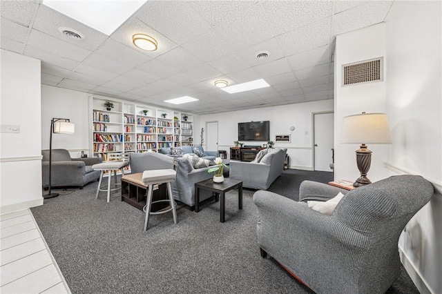 living room with a drop ceiling and carpet flooring